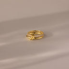 Duo Birthstone Tennis Linked Ring Set in Diamond (April) features two interlocking gold loops with small diamonds, displayed on a smooth, neutral surface.