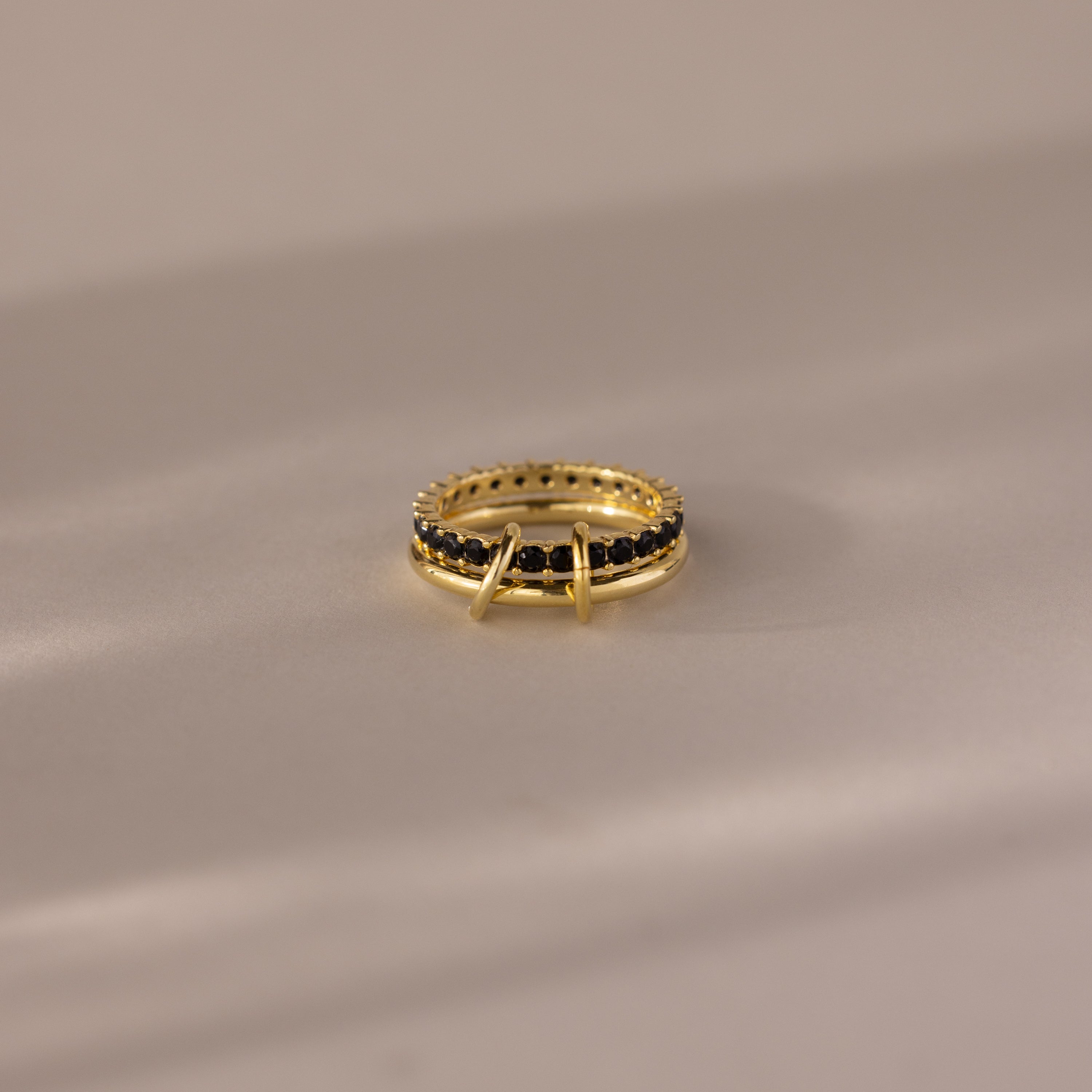 The Duo Birthstone Tennis Linked Ring Set in Onyx is displayed on a light, reflective surface.