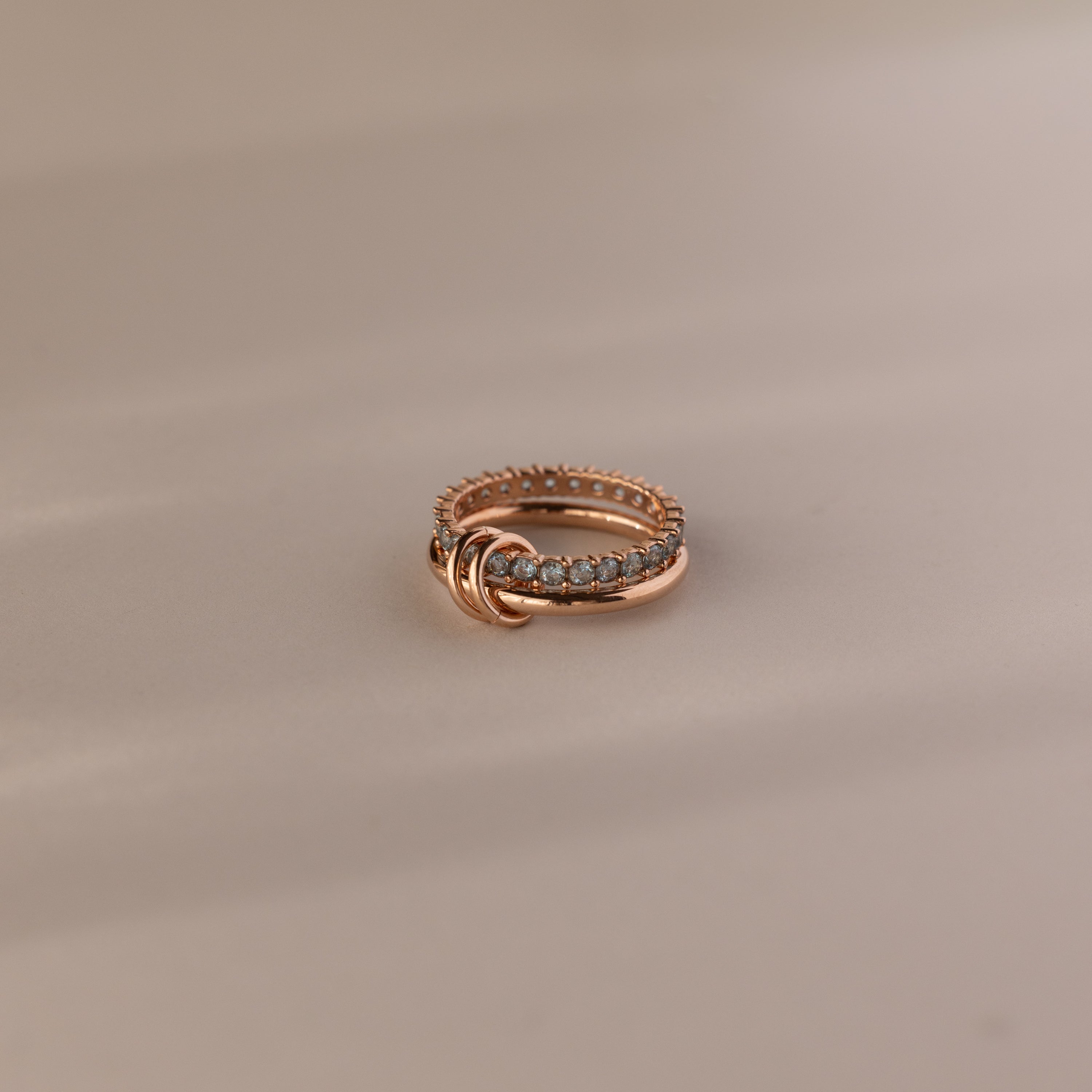 The Duo Aquamarine Tennis Linked Ring Set rests on a soft, beige surface.