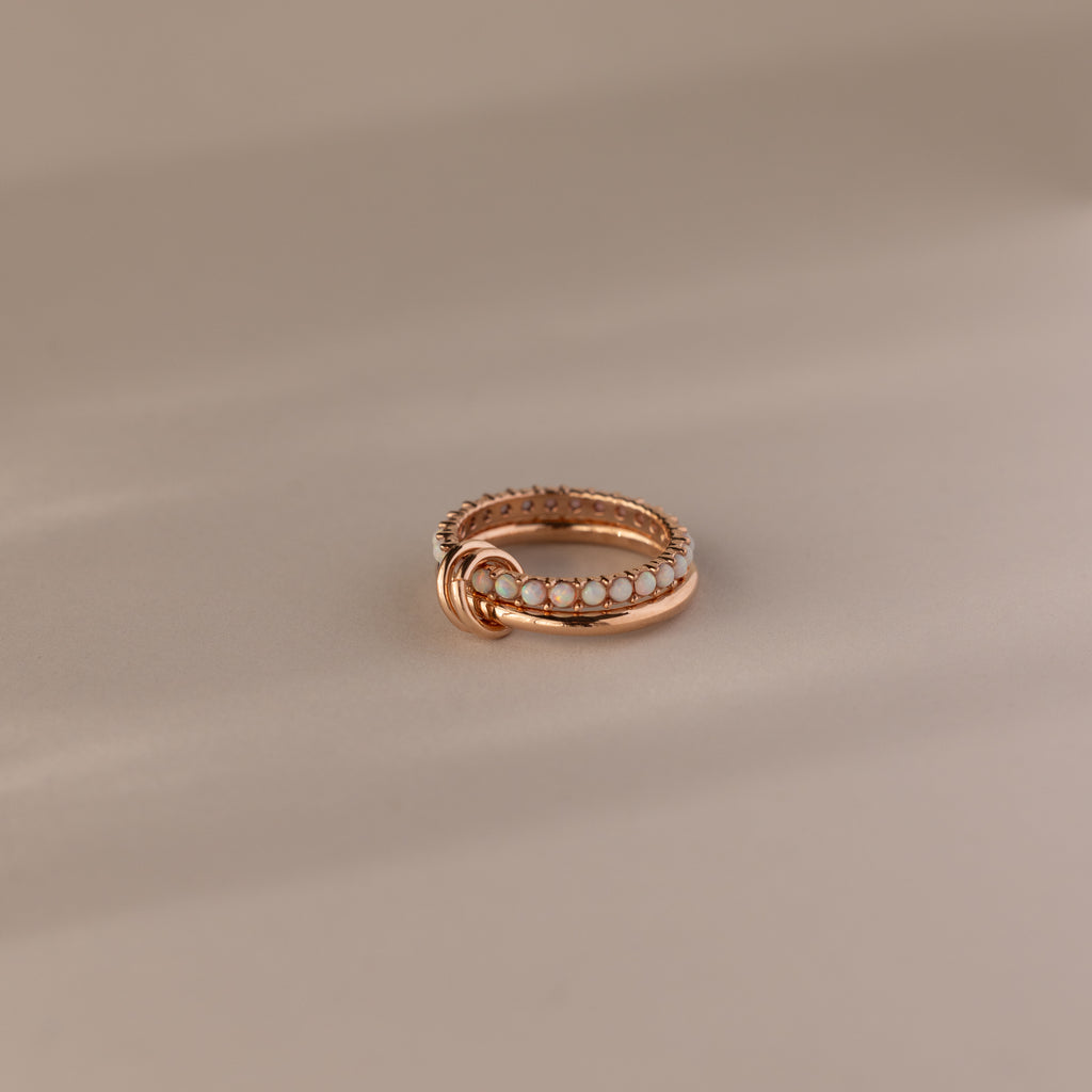 The Duo Opal Tennis Linked Ring Set features a delicate gold beaded design with interlocking loops, beautifully presented on a neutral background.