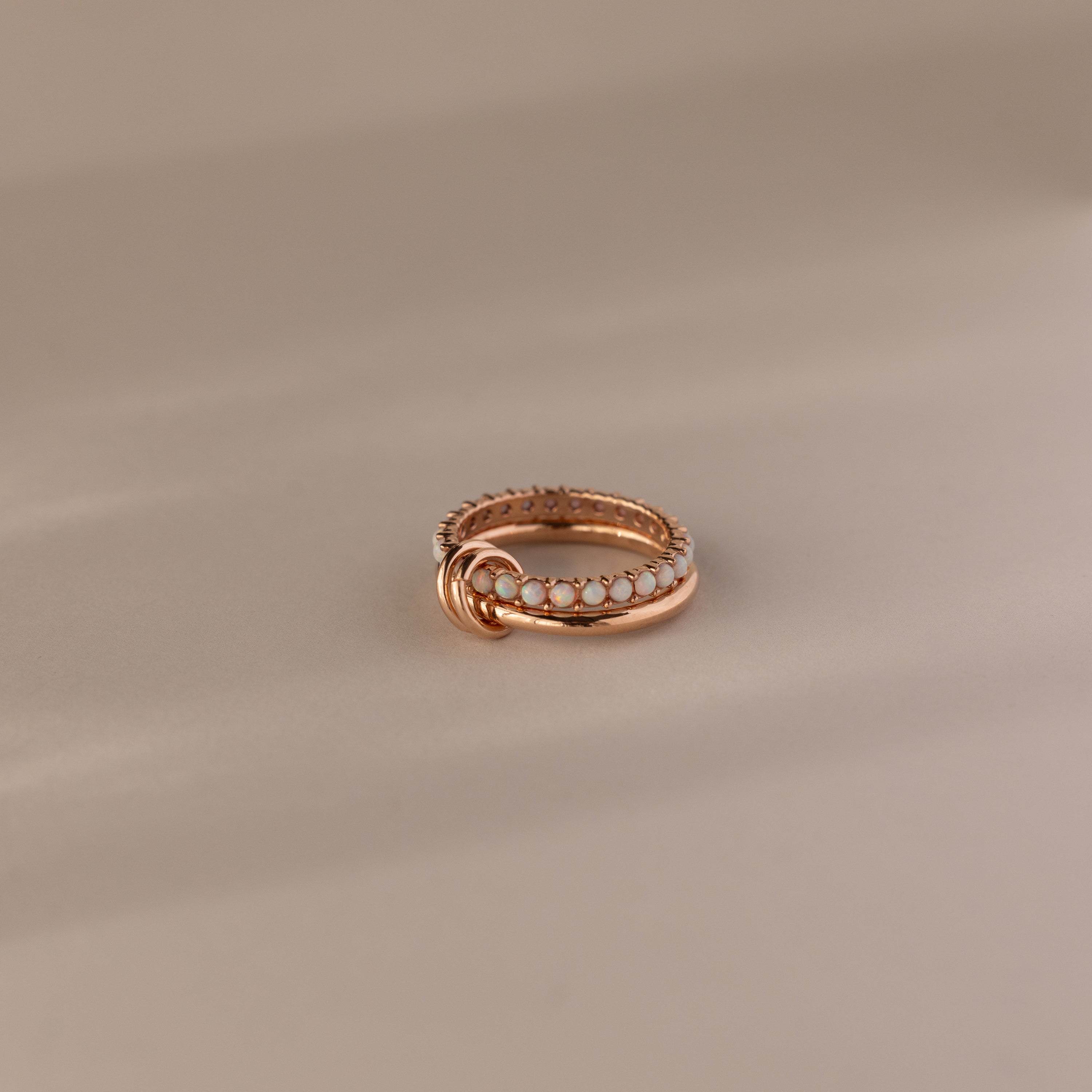 The Duo Opal Tennis Linked Ring Set features a delicate gold beaded design with interlocking loops, beautifully presented on a neutral background.