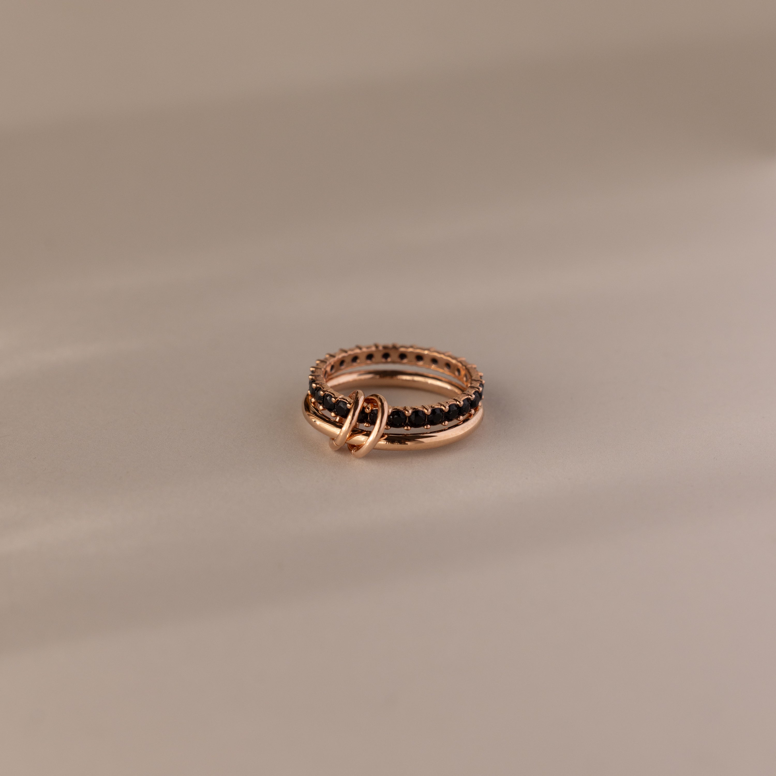 The Duo Onyx Tennis Linked Ring Set features two intertwined rings, one adorned with a textured, beaded design—an elegant pairing ideal for stacking with your favorite minimalist rings—beautifully displayed on a neutral background.