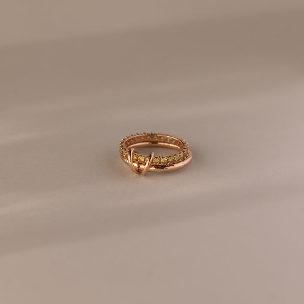 The Duo Topaz Tennis Linked Ring Set features small stones and a decorative loop, elegantly displayed on a neutral background.