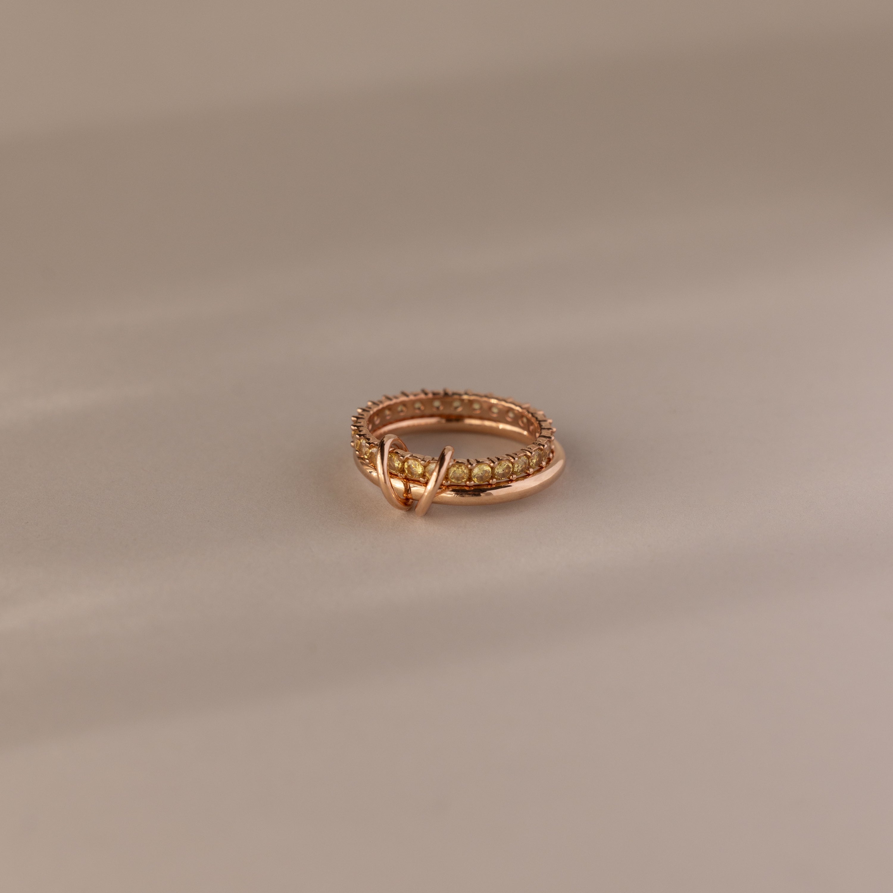 The Duo Topaz Tennis Linked Ring Set features small stones and a decorative loop, elegantly displayed on a neutral background.