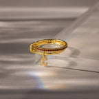 Linked Initial Garnet Ring Set features small red gemstones and a crescent moon charm, displayed on a clear acrylic stand—personalized jewelry perfect as a birthstone ring or unique accessory.