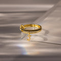 The Linked Initial Onyx Ring Set features a black stone accent and a dangling jeweled letter J charm, making it an elegant personalized jewelry piece or birthstone ring, beautifully displayed on a glass surface.