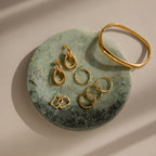 Gold earrings, rings, and a bracelet elegantly displayed on the Marble Jewelry Dish with soft natural lighting illuminating the green marble surface.