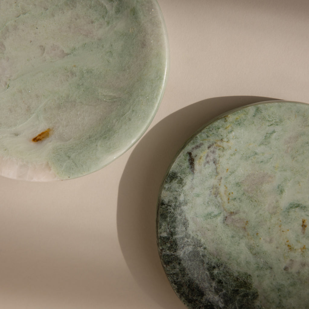 The Green Marble Jewelry Dish set features two round plates with unique green veining, resting on a neutral beige surface—ideal for displaying your favorite jewelry pieces in style.