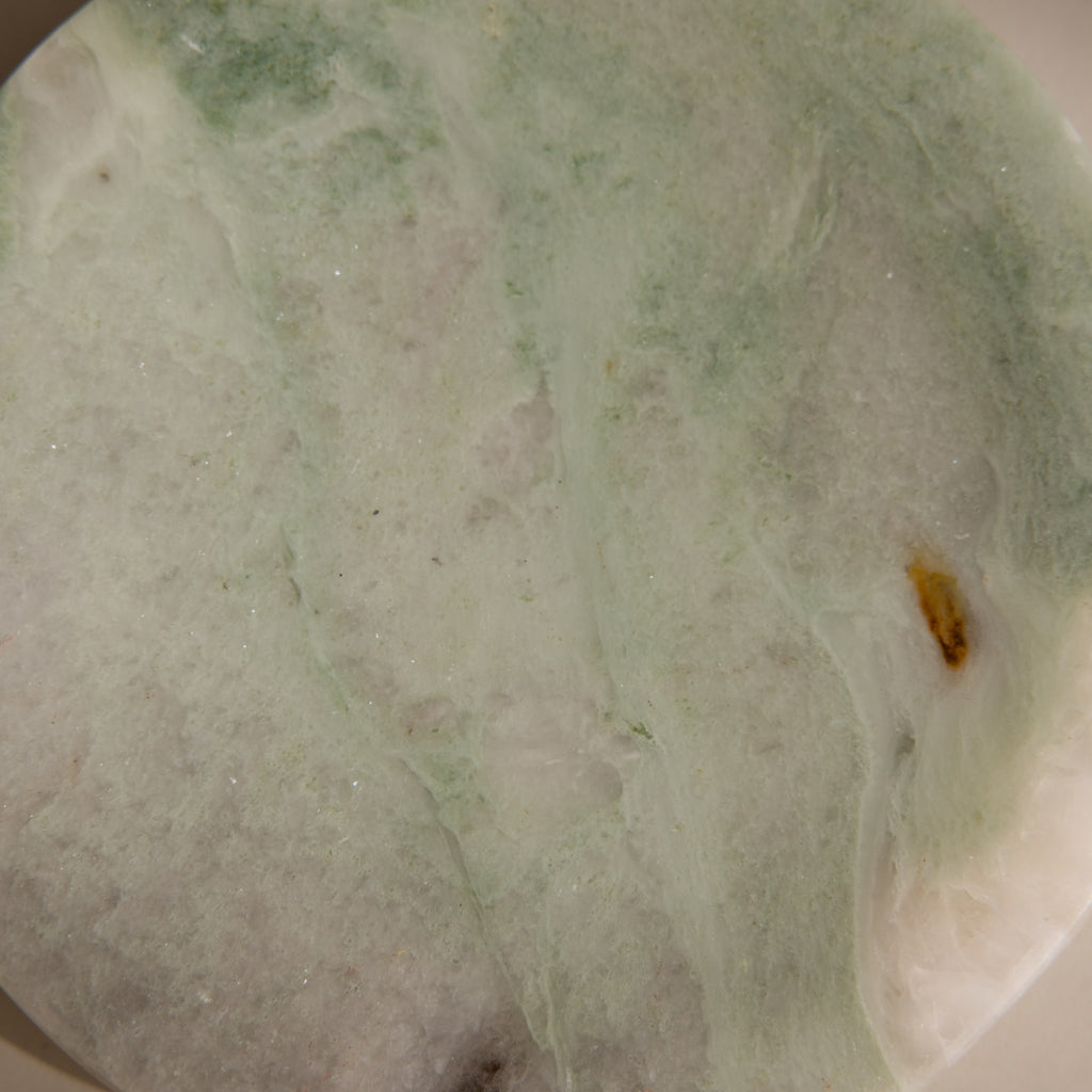 A close-up of the Green Marble Jewelry Dish, featuring a smooth pale green and white surface with subtle brown and yellow patches, perfect as a stylish jewelry holder.