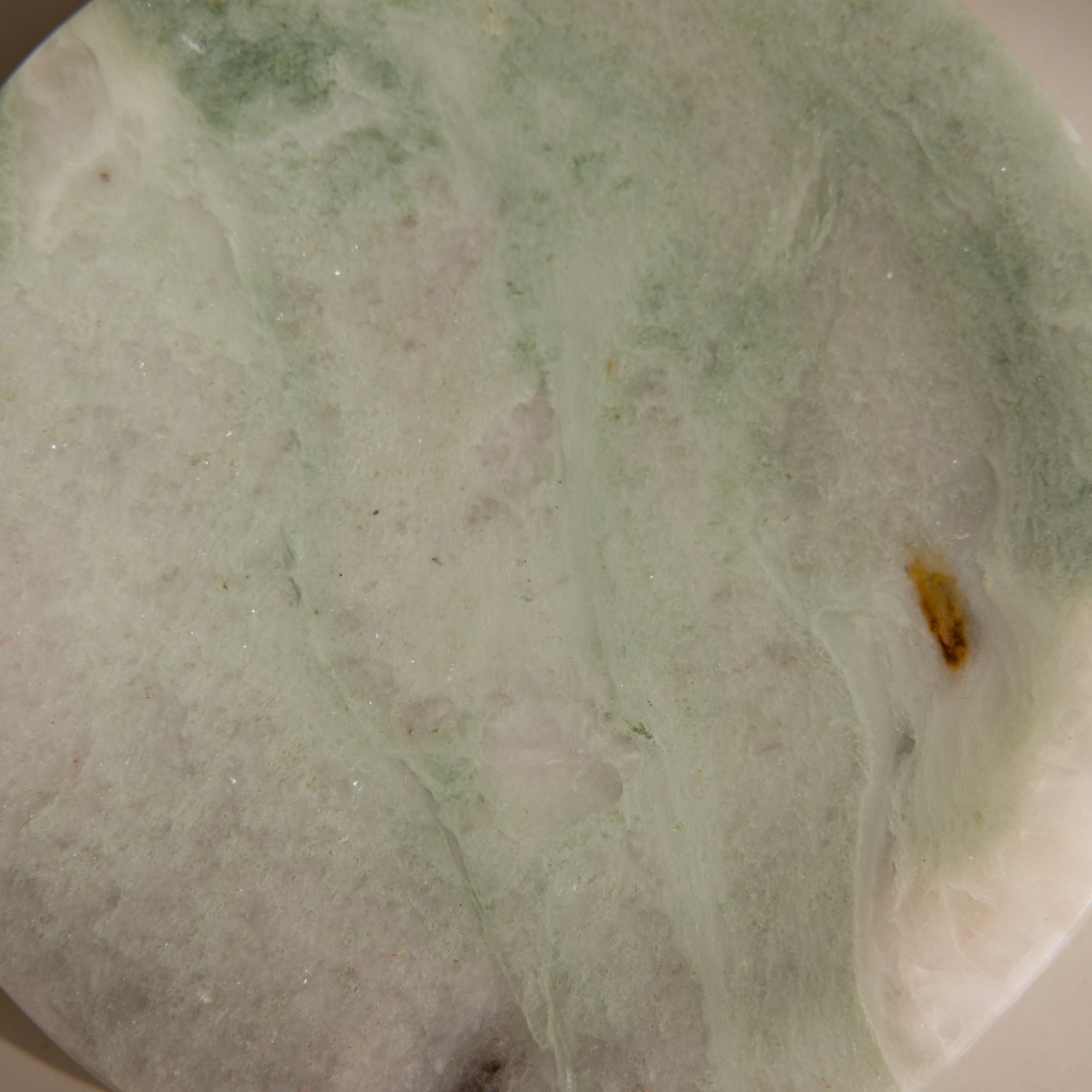 A close-up of the Green Marble Jewelry Dish, featuring a smooth pale green and white surface with subtle brown and yellow patches, perfect as a stylish jewelry holder.