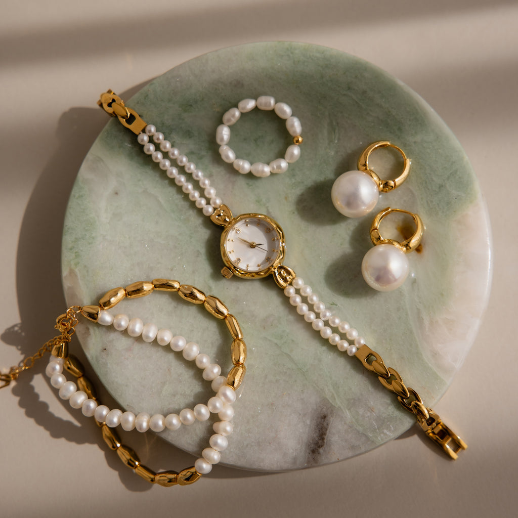 Gold and pearl jewelry—watch, rings, earrings, and bracelets—elegantly arranged on a Green Marble Jewelry Dish.