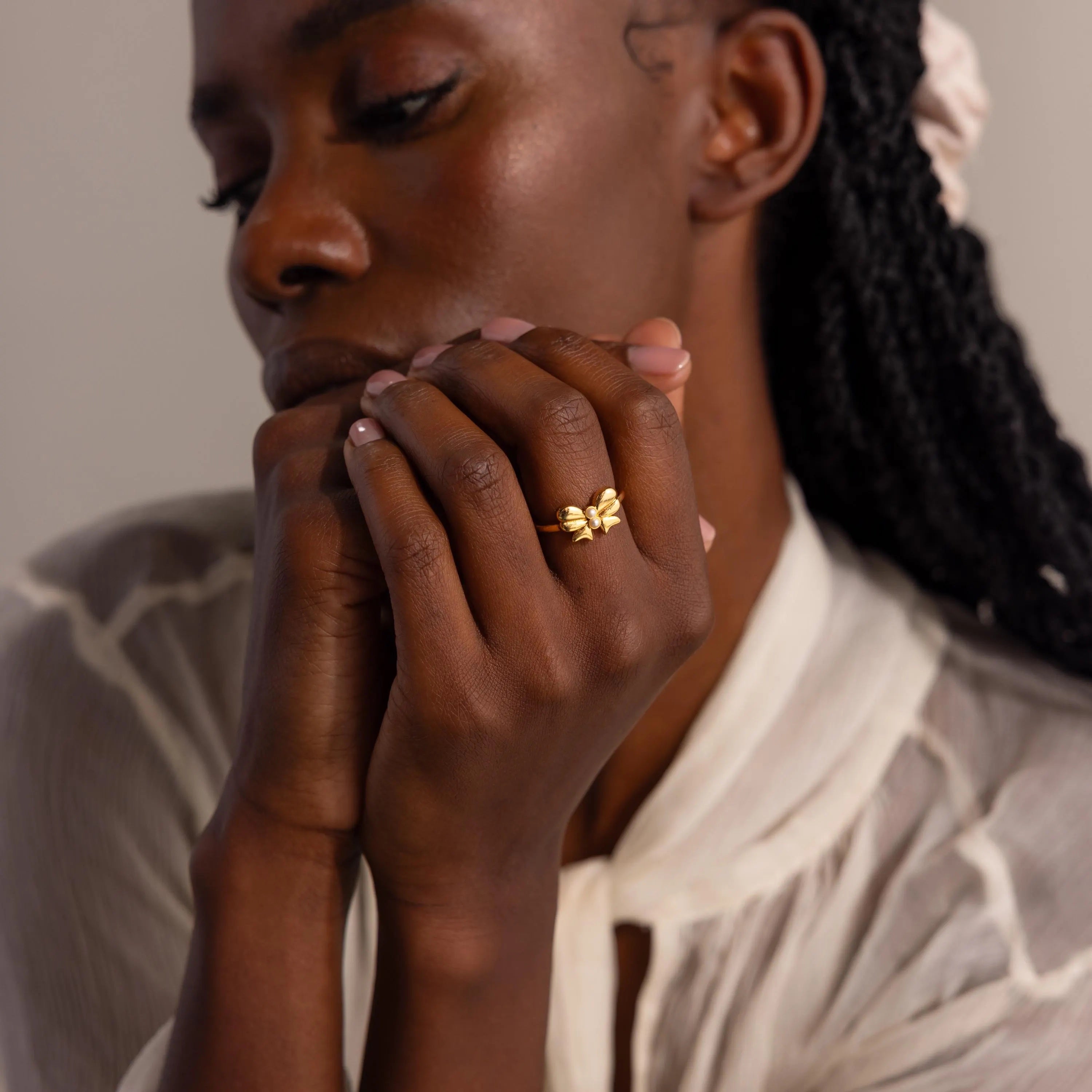 A close-up lifestyle portrait of a woman with the Bow Pearl Ring on her hand.