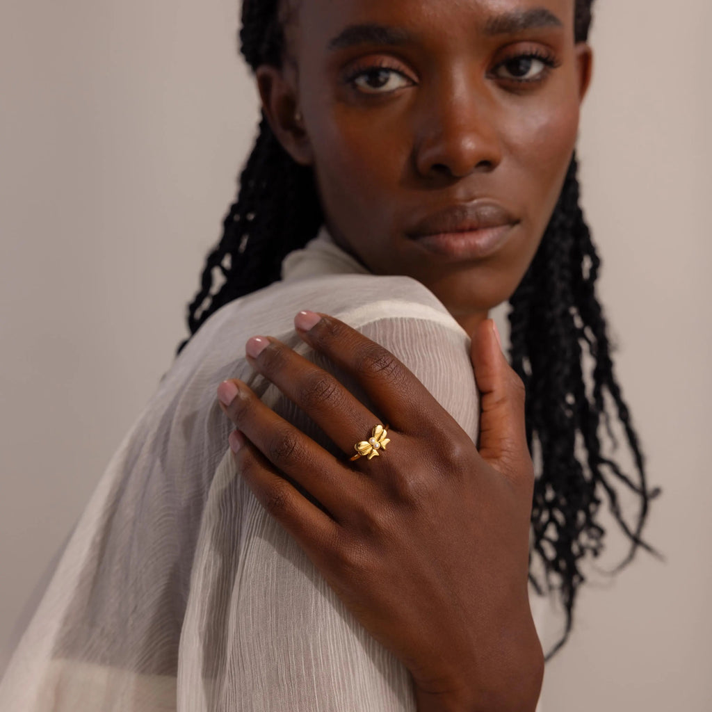 A woman wears the Bow Pearl Ring on her finger, positioned near her face.