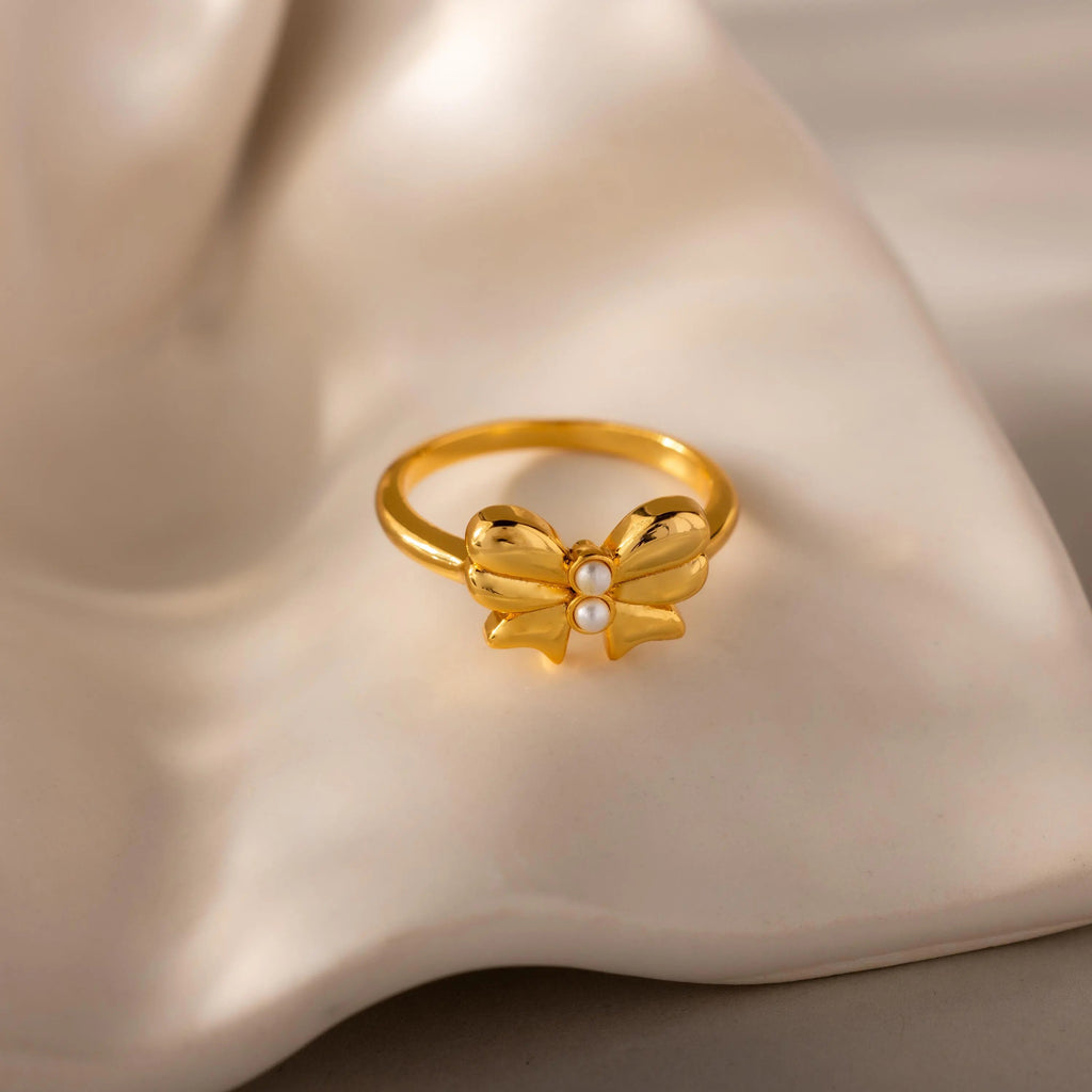 The Bow Pearl Ring rests elegantly on a ceramic surface.