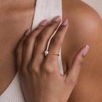 A hand with light pink nails models the elegant Open Pearl & Diamond Ring, gracefully resting on a white ribbed fabric top.