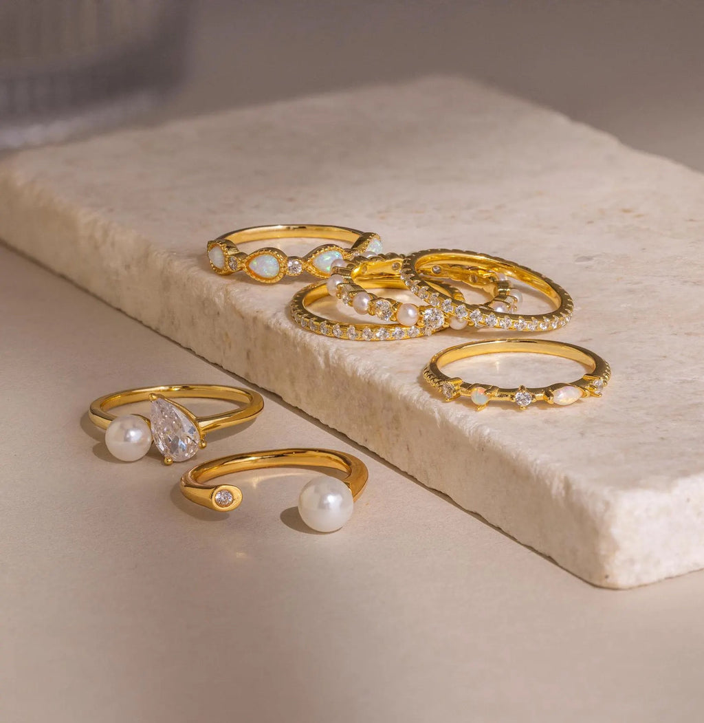 The Open Pearl & Diamond Ring, featuring pearls and diamonds, is displayed elegantly on a rectangular stone slab.