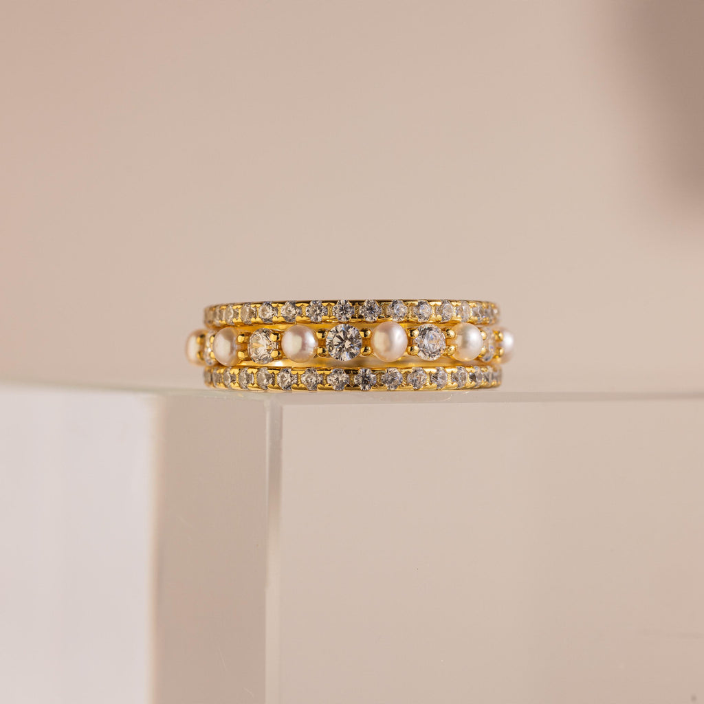 The Diamond Eternity Ring Set is elegantly displayed on a clear, glossy stand against a beige background.