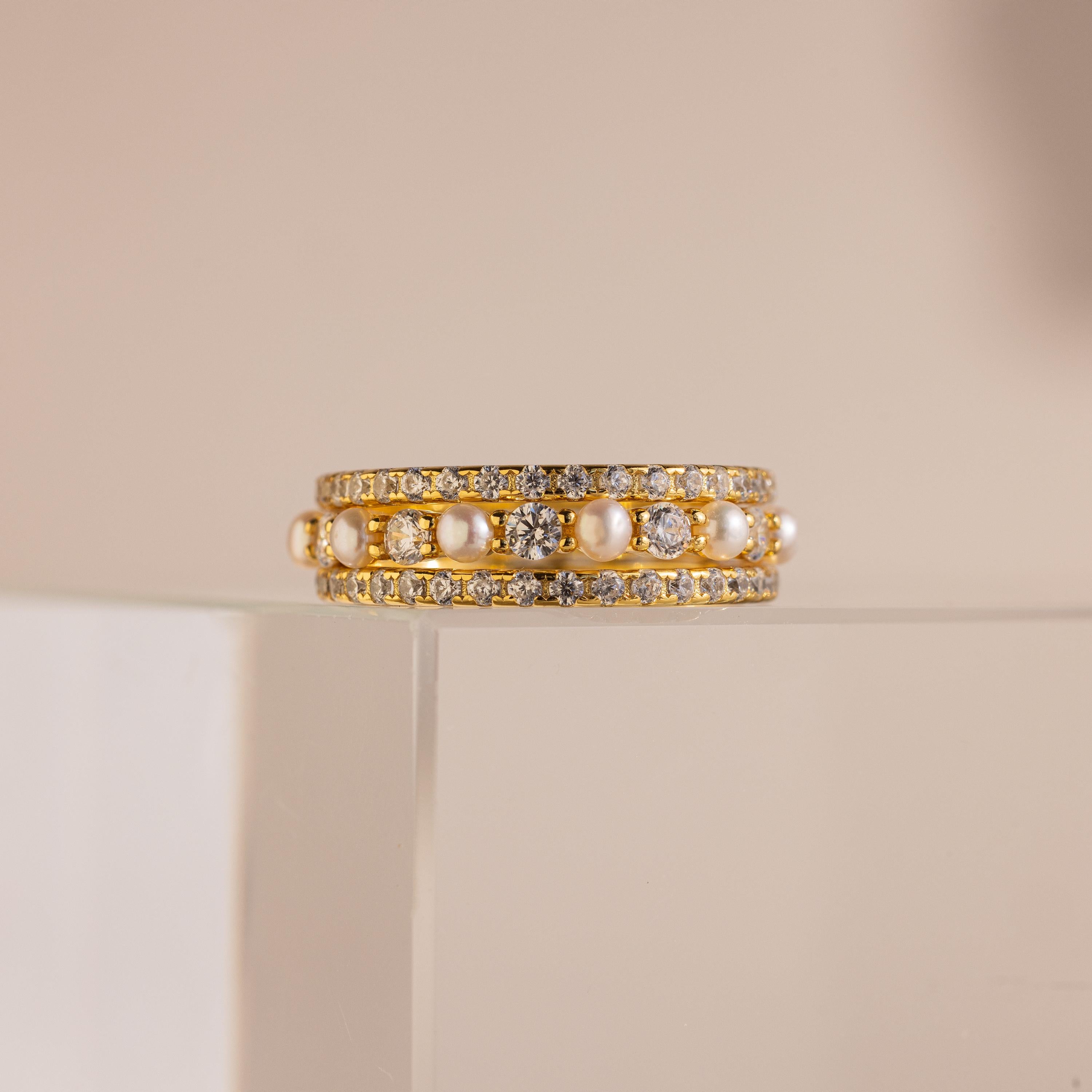 The Diamond Eternity Ring Set is elegantly displayed on a clear, glossy stand against a beige background.