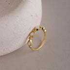 The Opal Diamond Teardrop Ring features teardrop-shaped opal stones set against a textured, light surface, evoking the charm of a vintage-inspired ring.