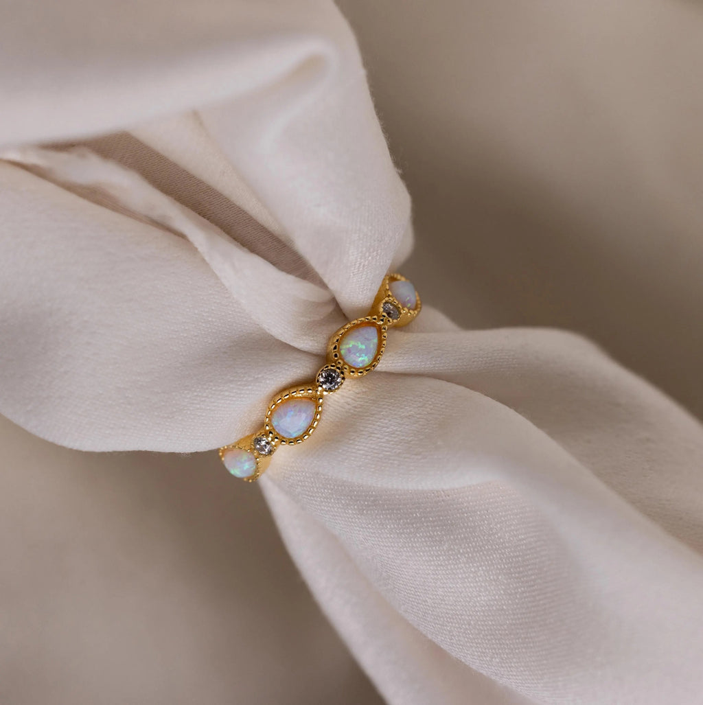 Opal Diamond Teardrop Ring, accented with sparkling diamonds and shown on soft white fabric, evokes vintage Art Deco elegance.