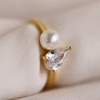 Close-up of the Pearl Diamond Ring on a soft fabric surface, emphasizing the glossy pearl and brilliant teardrop diamond.