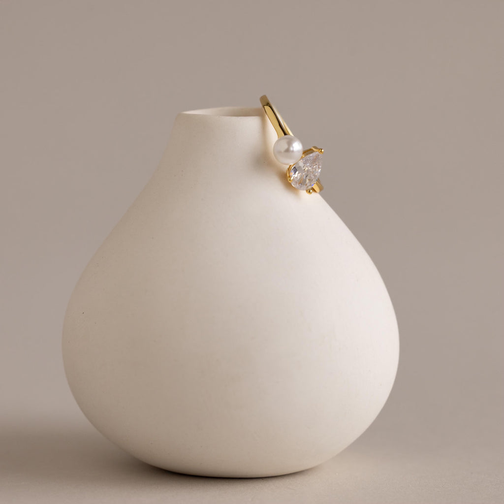 Our Pearl Diamond Ring displayed resting on a minimalist white ceramic vase, showing its elegant pearl and diamond accents.