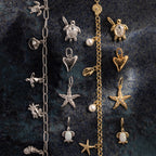 The Dainty Shark Tooth Charm in Silver features a sea-inspired design, perfect for coastal jewelry lovers, shown on a dark textured surface.