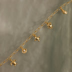 Seaside Charm Bracelet featuring gold chain and ocean-inspired charms—turtle, shell, fish, and seashell—displayed on a gray surface.