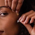 A person holds gold and silver Dainty Shark Tooth Charms near their face, showcasing both pieces and highlighting the coastal charm often found in beach jewelry.