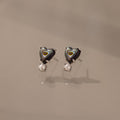 Abalone Pearl Heart Studs in Silver with concentric patterns, inspired by coastal jewelry, shown on a neutral, reflective surface.