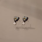 Abalone Pearl Heart Studs in Silver with concentric patterns, inspired by coastal jewelry, shown on a neutral, reflective surface.