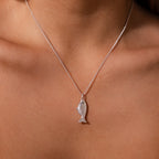 The Fish Pendant Necklace in Silver, inspired by the ocean and elegantly designed, rests on bare skin—a perfect accessory for effortless layering with any style.