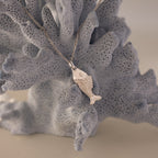 Fish Pendant Necklace in Silver, shown on textured light gray coral—perfect for layering and adding a coastal touch to any look.