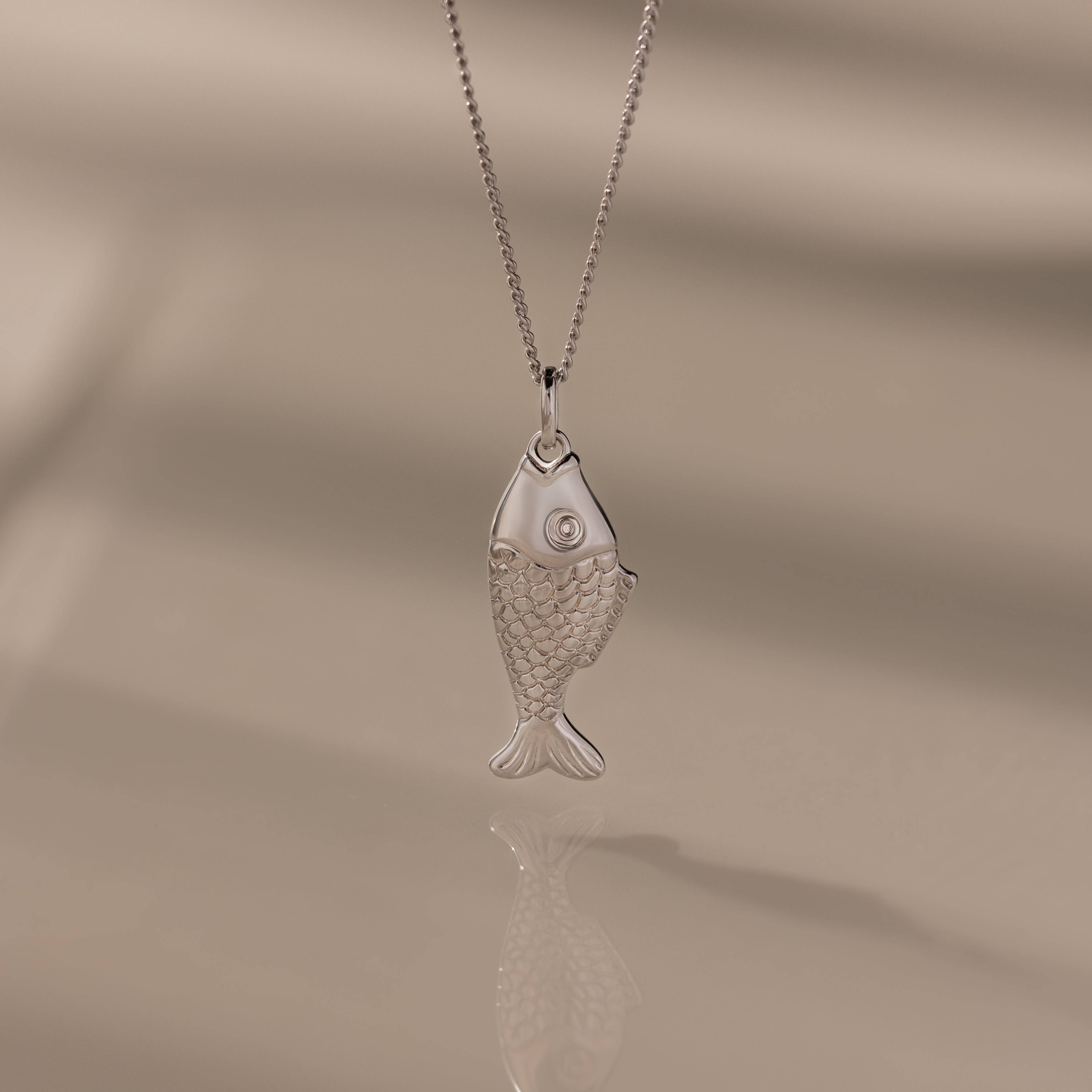 Fish Pendant Necklace in Silver features a textured scale pattern and is displayed on a soft, neutral background—ideal for layering and adding everyday elegance.