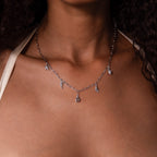 A woman wears the Ocean Charm Necklace in Silver with delicate seaside pendants on her bare neckline, adding a perfect coastal touch to any outfit.