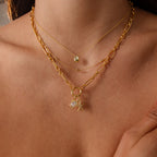 A woman wears layered gold necklaces, including the Diamond Turtle Charm in 18K Gold with a diamond-detailed shell and another necklace adorned with ocean-inspired charms and pearls.