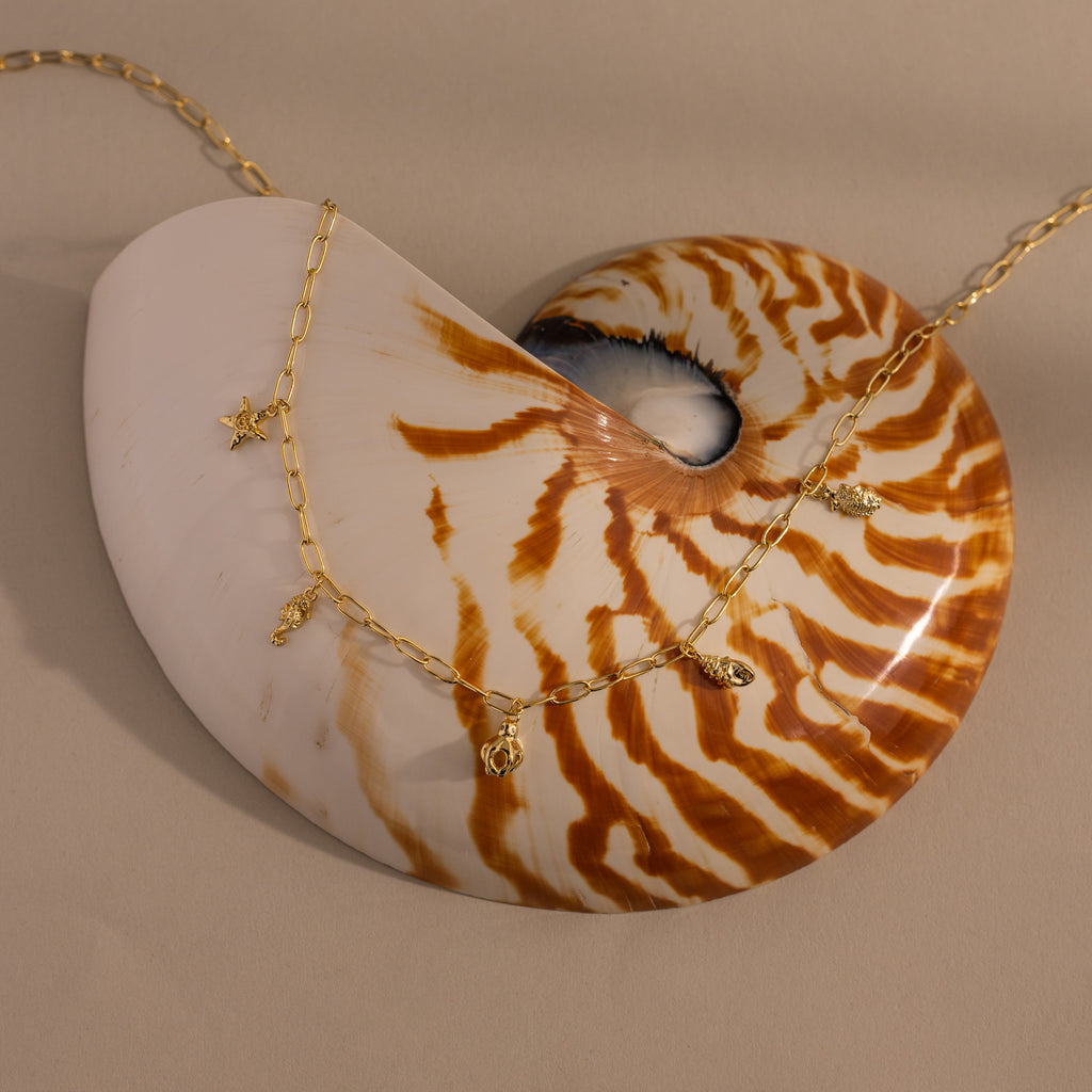 Ocean Charm Necklace in 18K Gold features sea-themed pendants, creating perfect summer jewelry for a beach-inspired look.