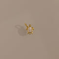 Diamond Turtle Charm in 18K Gold with a diamond-detailed shell, ocean-inspired, shown on a plain beige background.