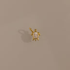 Diamond Turtle Charm in 18K Gold with a diamond-detailed shell, ocean-inspired, shown on a plain beige background.