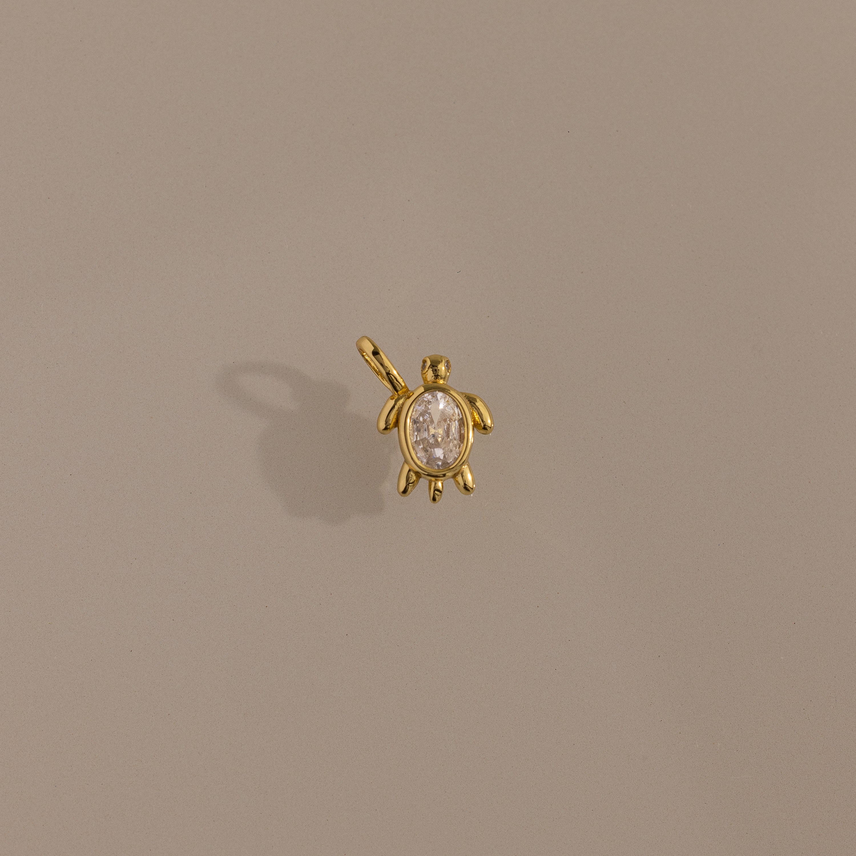 Diamond Turtle Charm in 18K Gold with a diamond-detailed shell, ocean-inspired, shown on a plain beige background.