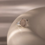 The Organic Fingerprint Signet Ring in Sterling Silver, featuring a round engraved top, rests on a smooth, light surface—a timeless, personalized jewelry piece.