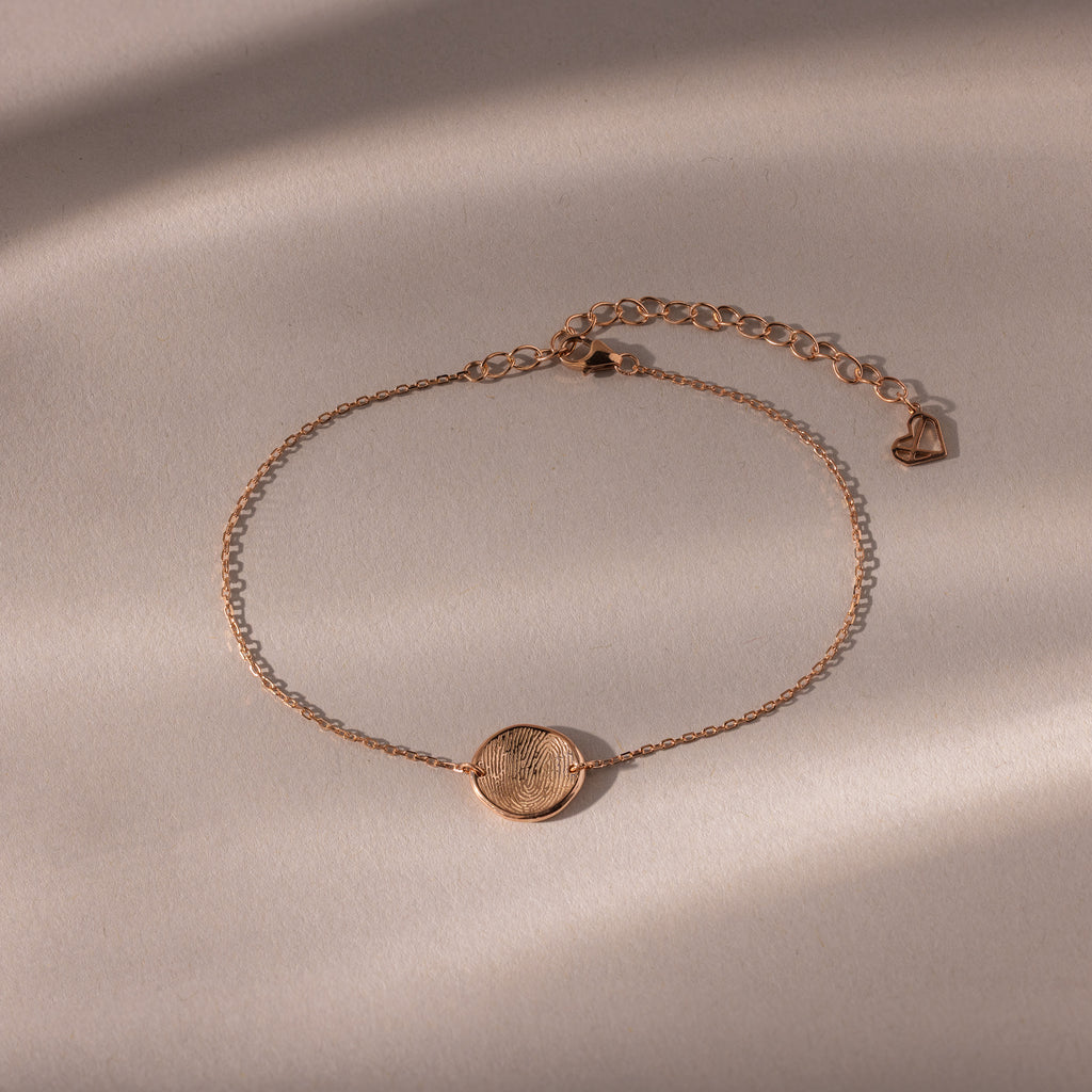 Dainty Organic Fingerprint Bracelet in Rose Gold with a round textured charm, shown on a neutral background with soft shadows—an ideal personalized gift.