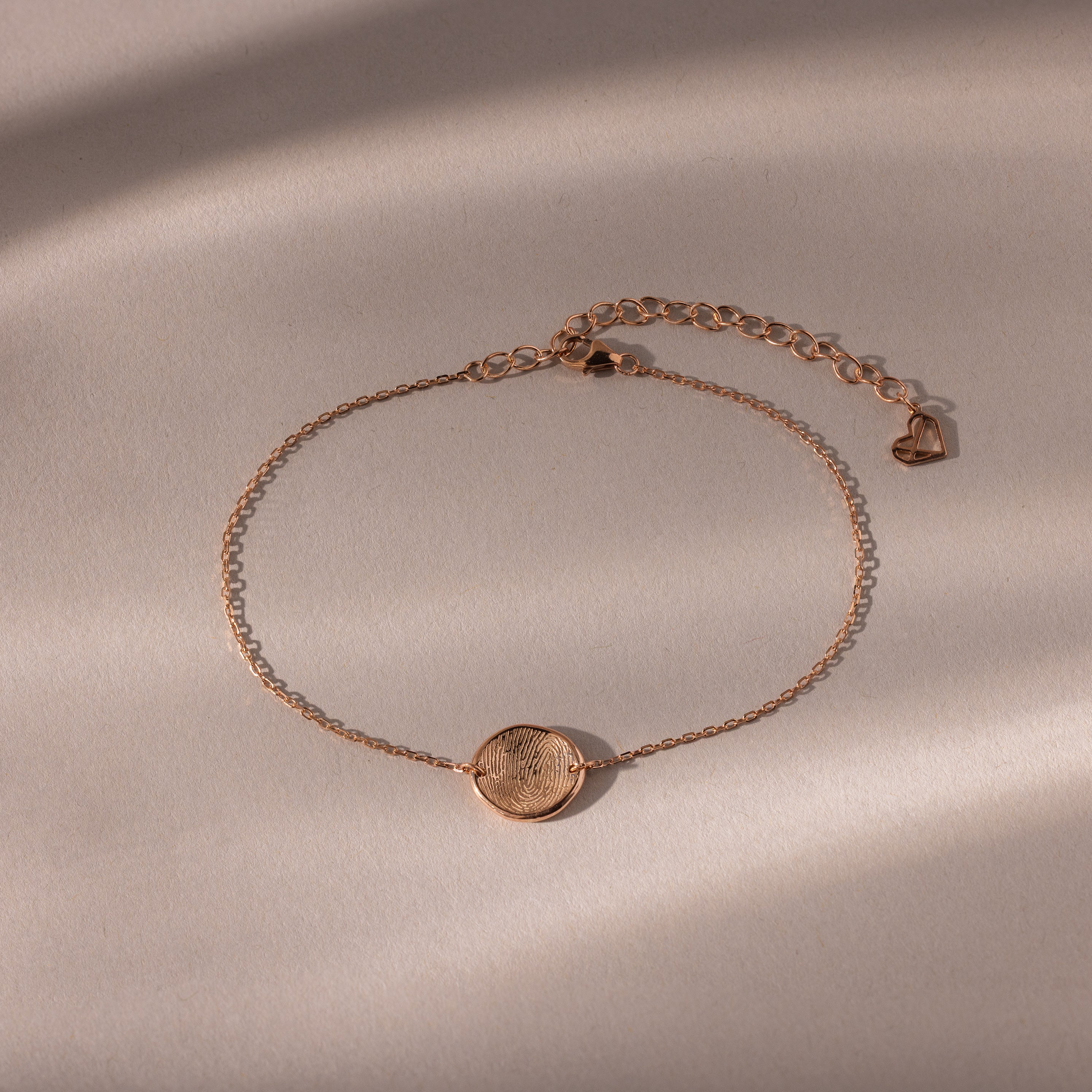 Dainty Organic Fingerprint Bracelet in Rose Gold with a round textured charm, shown on a neutral background with soft shadows—an ideal personalized gift.