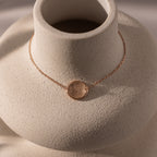 A dainty rose gold bracelet with an organic fingerprint charm, displayed on a textured white bust—an elegant piece of memorial jewelry and the perfect personalized gift.