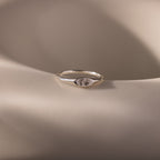 The Hand & Footprint Signet Ring in Sterling Silver, ideal as a baby keepsake, is displayed on a smooth beige surface.