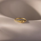 Hand & Footprint Signet Ring in 18K Gold displayed on a smooth, light-colored surface.
