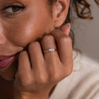 A woman smiles with her hand near her face, wearing the Hand & Footprint Signet Ring in Sterling Silver, featuring an engraved design.