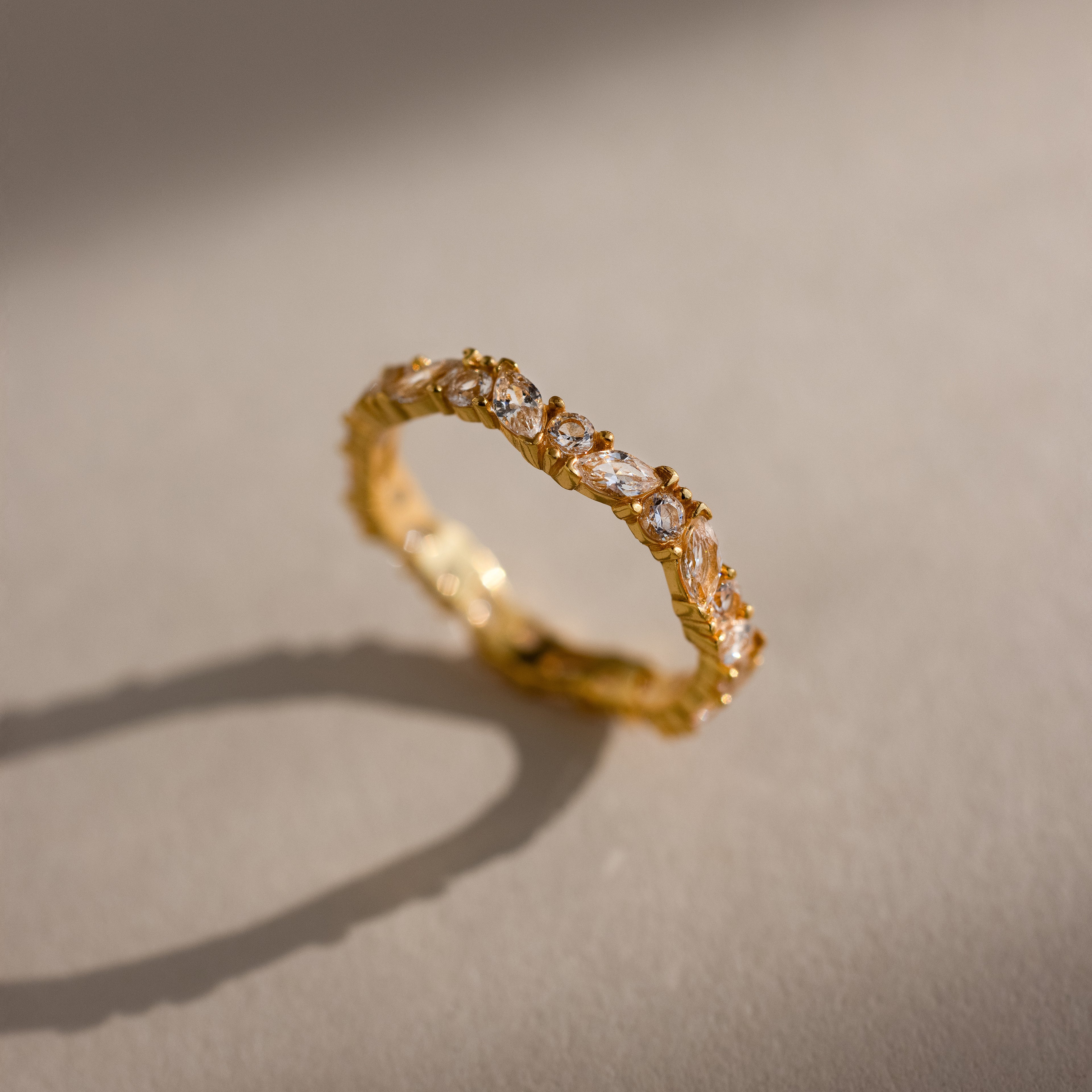 The Staggered Marquise Diamond Ring casts a shadow on a beige surface.