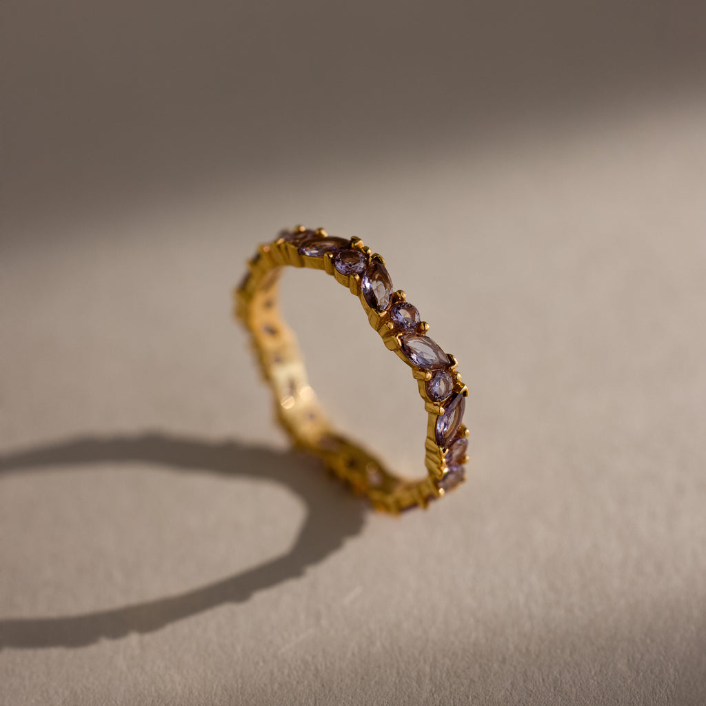 The Staggered Marquise Alexandrite Ring features upright marquise-cut gemstones on a neutral, softly lit surface, offering a unique twist on the classic eternity band.