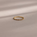 A delicate Dainty Marquise Birthstone Ring in Amethyst (February) rests on a soft beige surface, softly illuminated.